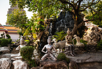 Stone statue in front of waterfall in Wat Pho buddhist temple, Bangkok, Thailand 