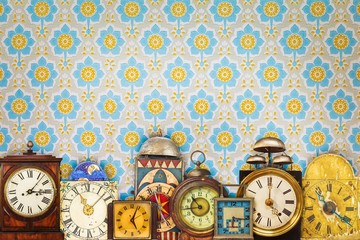 Colorful vintage clocks in front of retro wallpaper