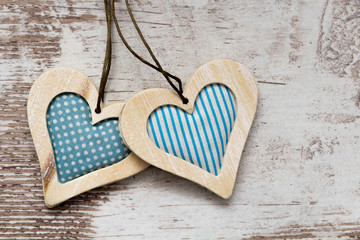 two blue colored wooden hearts on white wooden background texture