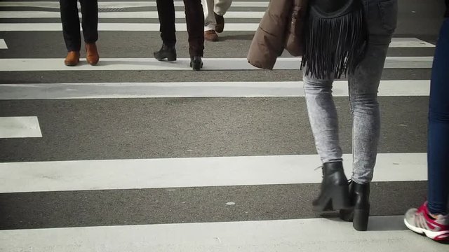 Slow motion footage of people crossing a street on a pedestrian crossing.