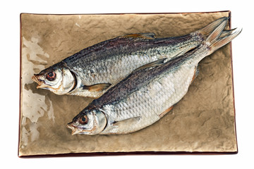 Dried salted bream fish on the brown plate.