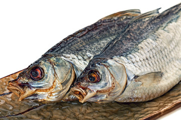 Dried salted bream fish on the brown plate.