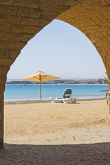 Sunbed on a tropical beach through archway