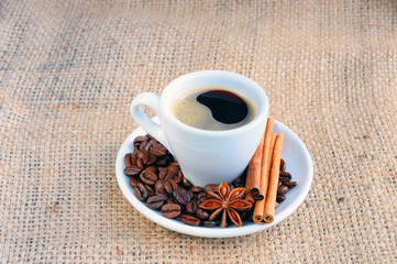  A hot Cup of coffee on a saucer on the background of burlap.