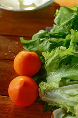 Red tomatoes and green lettuce on a wooden table. Useful vegetables. Healthy lifestyle. Selective focus.