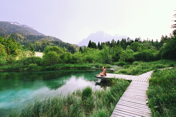 Woman doing yoga and meditating in lotus position on the nature.