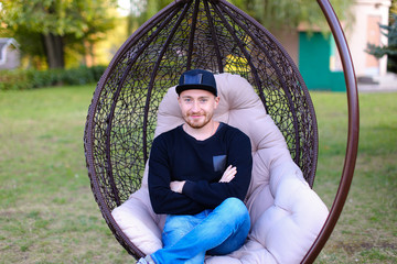 Young boy sits in suspended chair with legs crossed, looks and s