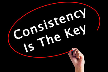 Hand Writing Consistency is The Key with a marker over transparent board.