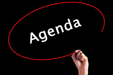 Hand Writing Agenda with a marker over transparent board.