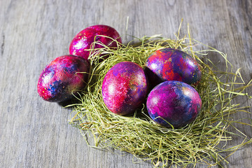 Easter decoration eggs on a hay on a gray background