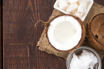 Coconut with coconut oil in jar on wooden background