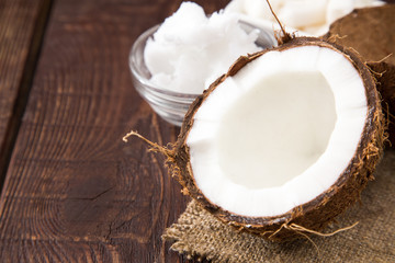 Coconut with coconut oil in jar on wooden background