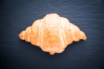 Fresh croissant on a black slate background. Top view