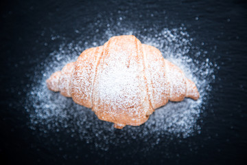 Fresh croissant on a black slate background. Top view