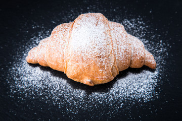 Fresh croissant on a black slate background. Top view
