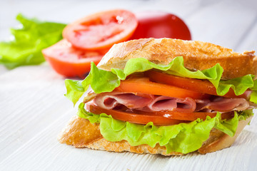 butterbrod with salad tomatoes and dried meat on a white wooden table