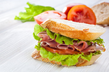 butterbrod with salad tomatoes and dried meat on a white wooden table
