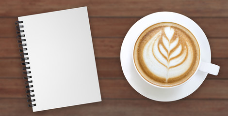Hot coffee latte art and blank notebook on wood background top view isolated on white background