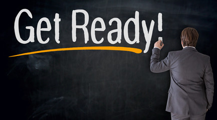 Businessman writes get ready on blackboard concept