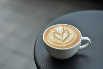 Coffee cup with latte art on the black metal table