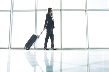 Fototapeta na wymiar Business woman with laggage bag walking in airport