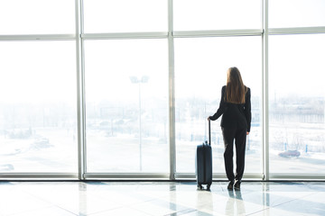 Fototapeta na wymiar Businesswoman in airport with laggage looking at terminal panoramic windows