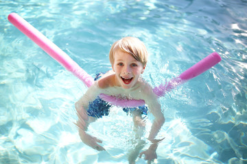 Happy Young Child Floating in Swimming Pool