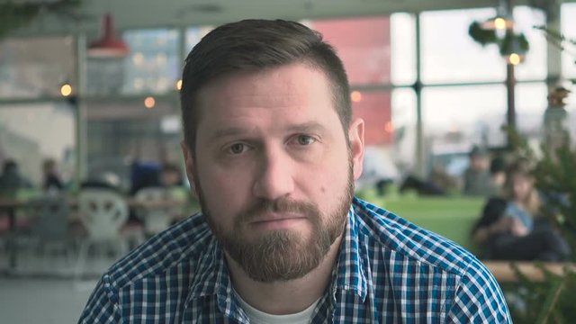 Serious man looking to camera, portrait, in cafe, very close steadicam shot