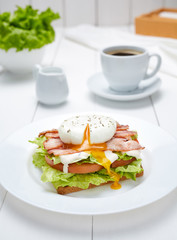 Poached egg on bread with bran, lettuce, tomato and bacon. Low carb diet. A healthy breakfast.