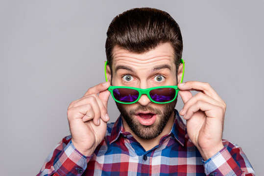 A close up portrait of a young handsome man touching his sunglasses and staring at something hypnotising
