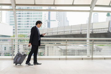 Young asian businessman using smartphone while walking outside business district