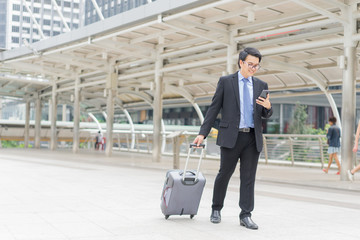 Young asian businessman using smartphone while walking outside business district