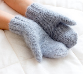 Gray blue mittens connected by hand from wool on a woman's arm