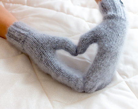 Gray blue mittens connected by hand from wool on a woman's arm