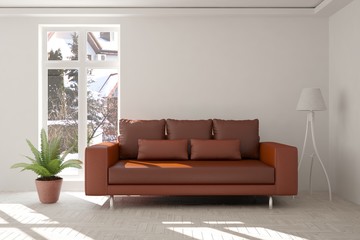 White room with sofa and winter landscape in window. Scandinavian interior design