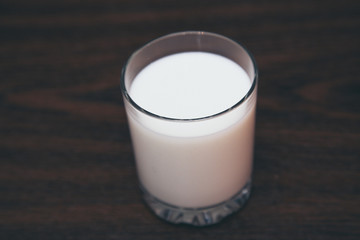 glass filled with milk on a wooden board