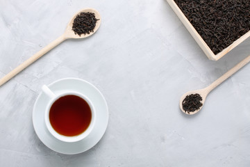 Cup of tea wooden box and spoons on concrete background.