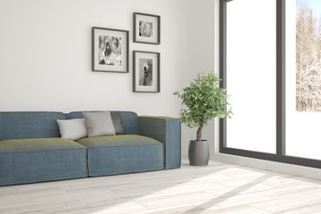 White room with sofa and winter landscape in window. Scandinavian interior design