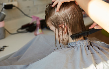 Fototapeta premium Hairdresser making a hair style to cute little girl.