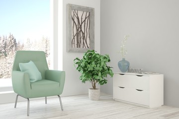 White room with armchair and winter landscape in window. Scandinavian interior design