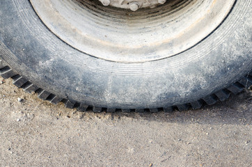 Rubber truck tire tread close up on asphalt road surface