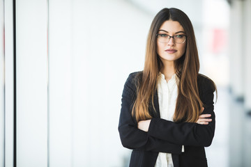 Smiling young Business woman crossed arms, standing against office