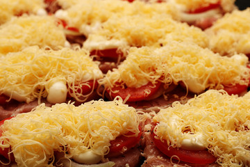 Raw fresh meat sliced with cheese, tomato sauce and spices on a baking tray, ready to be placed in the oven.