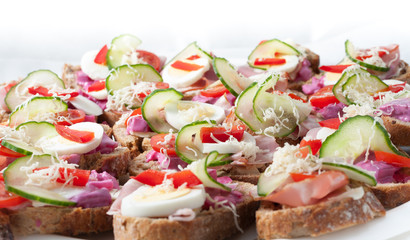 sandwiches with vegetables, ham and grated cheese on a tray
