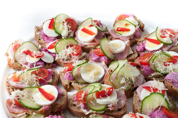 sandwiches with vegetables, ham and grated cheese on a tray