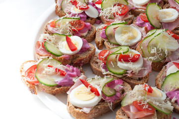 sandwiches with vegetables, ham and grated cheese on a tray