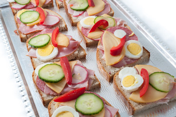 sandwiches with vegetables, ham and grated cheese on a tray