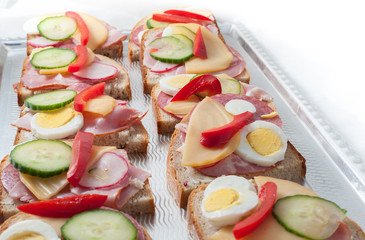 sandwiches with vegetables, ham and grated cheese on a tray