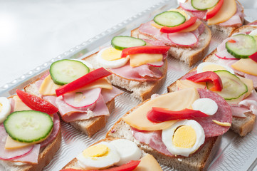 sandwiches with vegetables, ham and grated cheese on a tray