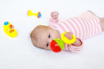 Cute baby girl playing with colorful rattle toys